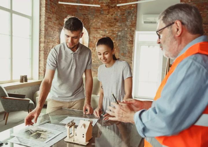 Homeowner consulting with a contractor over blueprints for a home renovation project.
