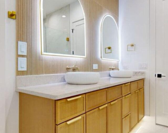 Twin sink vanity with wood cabinetry and LED mirrors