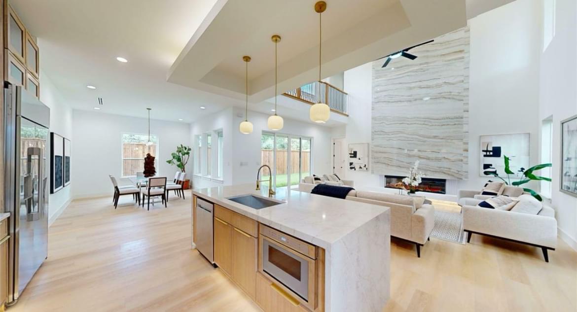 Renovated open kitchen with island, pendant lights, and living area view