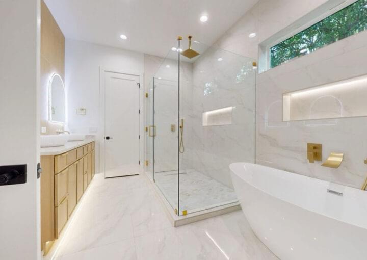 White marble bathroom remodel with soaking tub and gold hardware