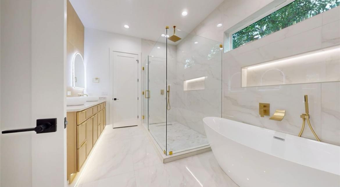 White marble bathroom remodel with soaking tub and gold hardware