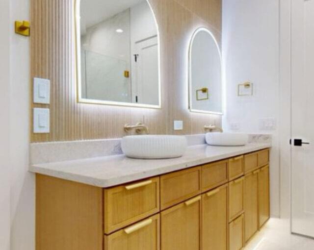 Twin sink vanity with wood cabinetry and LED mirrors